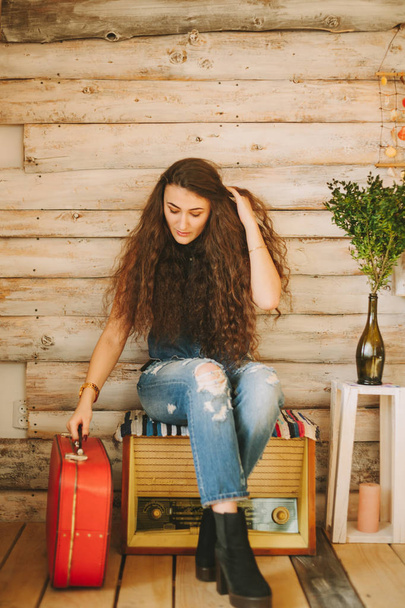 Portret van een meisje met lang, krullend, natuurlijke haren. Rood koffer - Foto, afbeelding