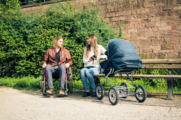 Young Parents In Wheelchair With Baby Stroller In The Park - Foto, Imagen