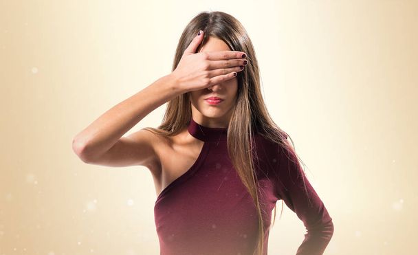 Young teenager girl covering her eyes on ocher background - Photo, Image