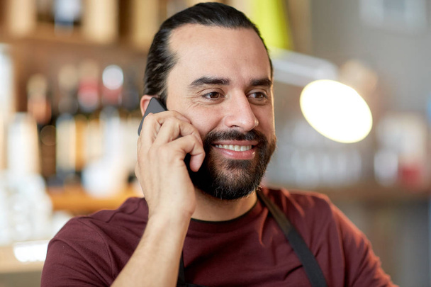 onnellinen mies tai tarjoilija baarissa soittamalla älypuhelimeen
 - Valokuva, kuva
