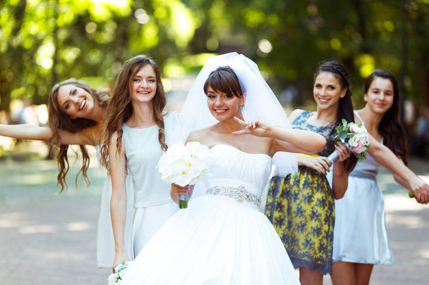 Bride rises the sign of virctory posing with pretty bridesmaids  - Фото, зображення