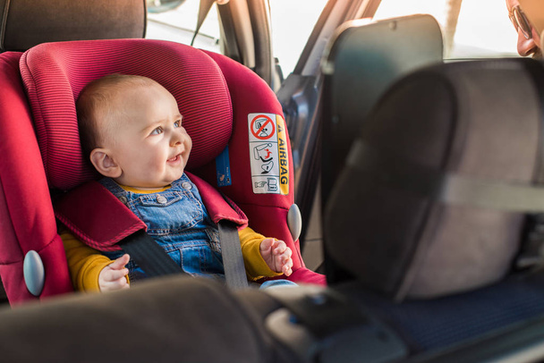 Vater schnallt sein Baby im Autositz an - Foto, Bild