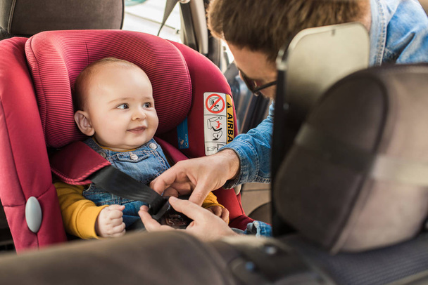 Father fasten his baby in car seat - Foto, imagen