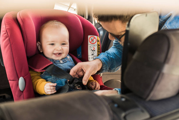 Babası onun bebek araba koltuğuna kemerlerinizi bağlayın - Fotoğraf, Görsel