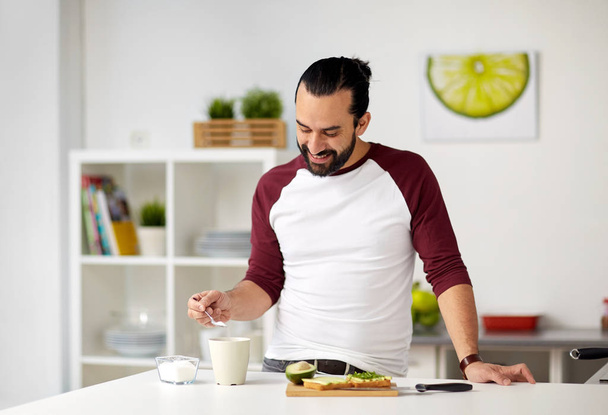 man adding sugar to cup for breakfast at home - Foto, immagini