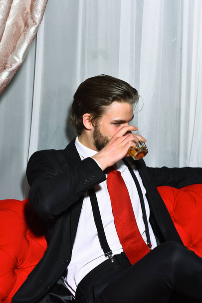 bearded man, businessman holding glass of whiskey in red tie - Фото, изображение