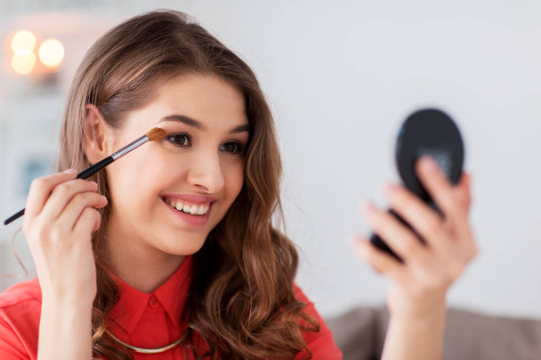 woman with eye shadow brush and mirror does makeup - Foto, immagini