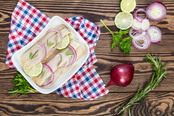Sliced herring fillets, cut onion and lime - Photo, Image