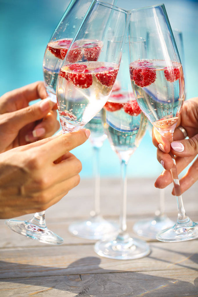 Mains avec des verres de champagne à la framboise
 - Photo, image