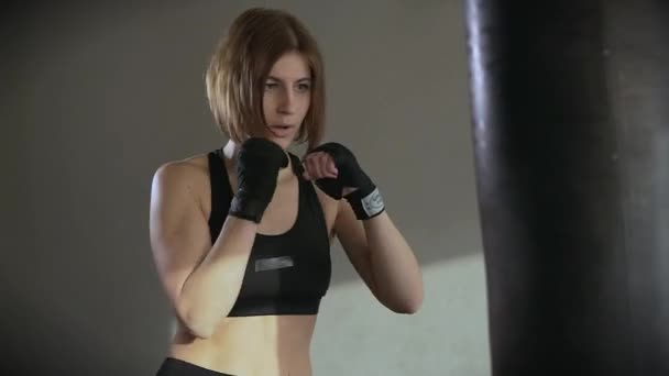 Sportowe kobieta jest zaangażowana w boksie, pociągi z worek bokserski w klubie fitness - Materiał filmowy, wideo