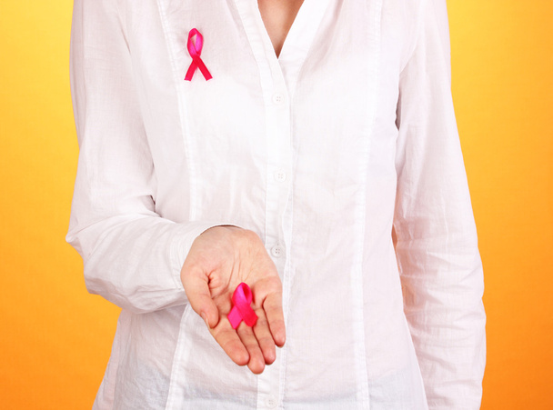Woman with pink ribbon in hands on orange background - Foto, immagini