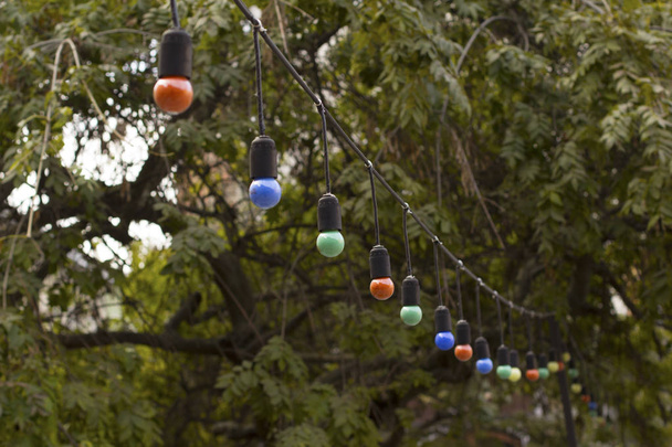 Гирлянды с цветными лампами, висящие на летней террасе
 - Фото, изображение