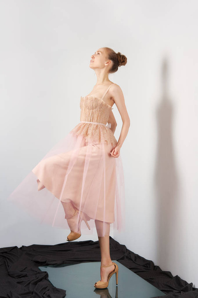 Fashion model lifting leg in peach fluffy dress - Foto, afbeelding