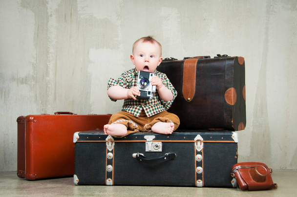 Child sits on a suitcase and with a camera in his hands - Photo, Image