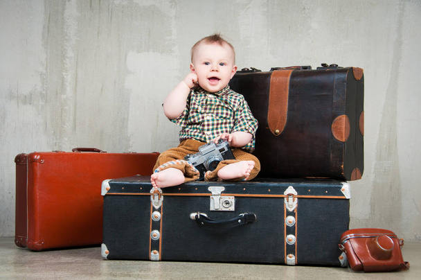 Gyermek ül és fényképezőgéppel a kezében egy bőrönd - Fotó, kép