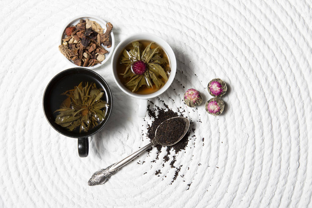 Food background with different black and green dry tea, rose buds cup of hot tea and iron teapot over dark wooden background. Tea drinking concept. Top view. Square image - Photo, Image