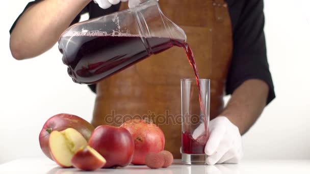 Mann gießt Saft in Glas auf Tisch mit Früchten - Filmmaterial, Video