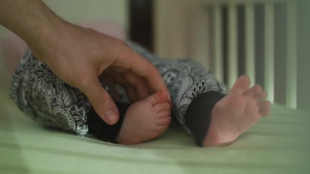 Padre mano acariciando su bebé pies
 - Imágenes, Vídeo