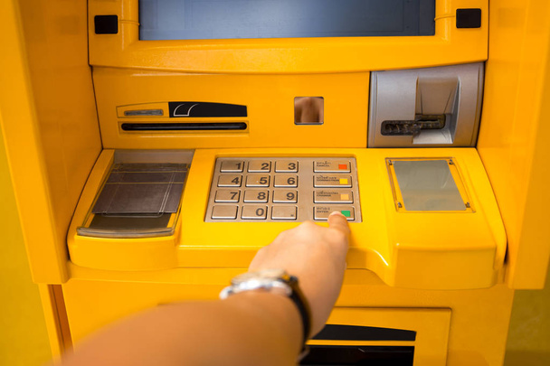 Käsi painamalla enter painiketta pankkiautomaatilla
 - Valokuva, kuva