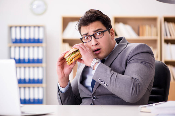 Hongerige grappige zakenman die junk food sandwich eet - Foto, afbeelding