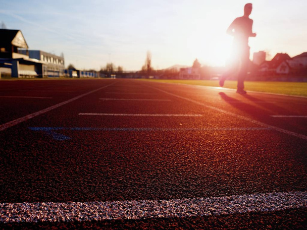 Спортсмен у тренуванні на дивовижному заході сонця на стадіоні
 - Фото, зображення