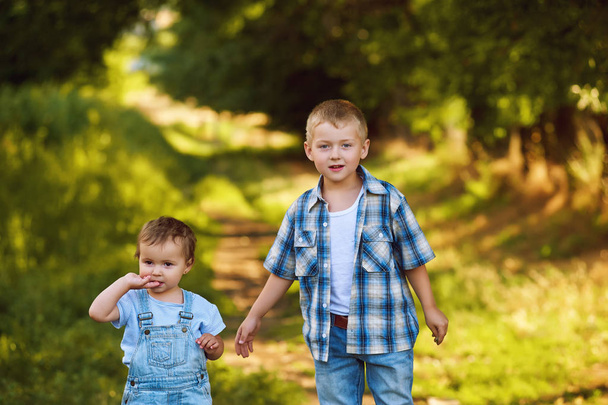 τα παιδιά με τα πόδια σε ένα πάρκο, αδελφός και αδελφή για μια καλοκαιρινή βόλτα - Φωτογραφία, εικόνα