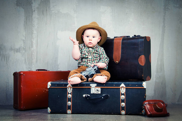 Child sits on a suitcase and with a camera in his hands - Foto, Imagen