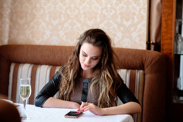 Beautiful girl with a phone in the restaurant. - Photo, Image