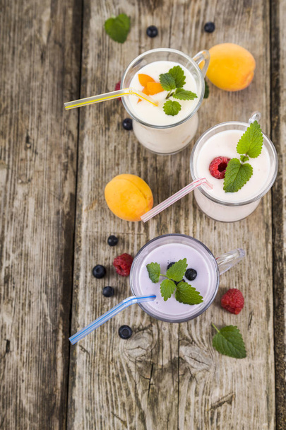 Three glasses with smoothies  or yogurt with fresh berries on a  - Fotoğraf, Görsel