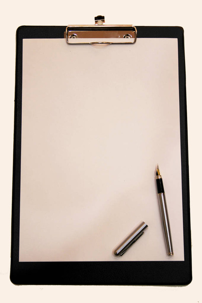 Valkoinen paperiarkki, johon on kiinnitetty kynä kansioon
 - Valokuva, kuva