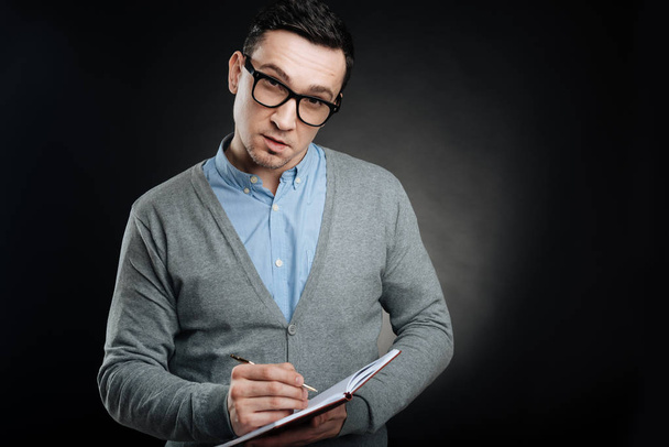 Serious brunette male person making some notes - 写真・画像