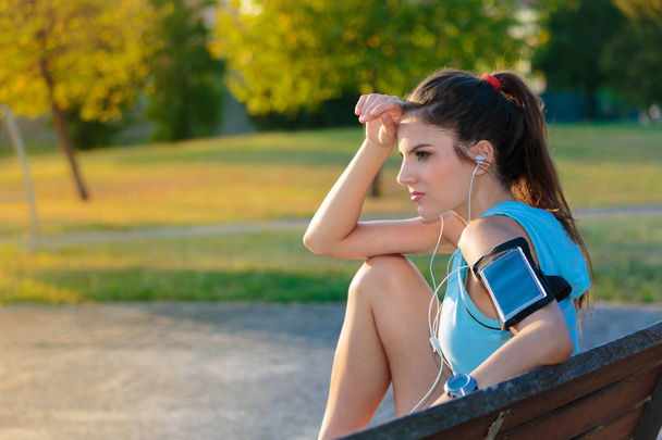 Žena poslechu hudby pomocí sluchátek ze svého chytrého telefonu - Fotografie, Obrázek