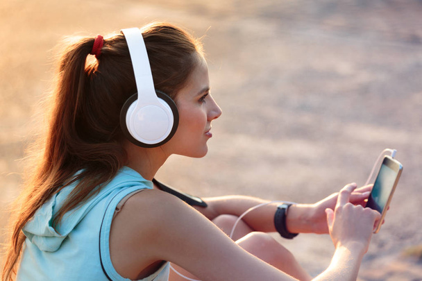 Γυναίκα να ακούτε μουσική με ακουστικά από το έξυπνο τηλέφωνο - Φωτογραφία, εικόνα