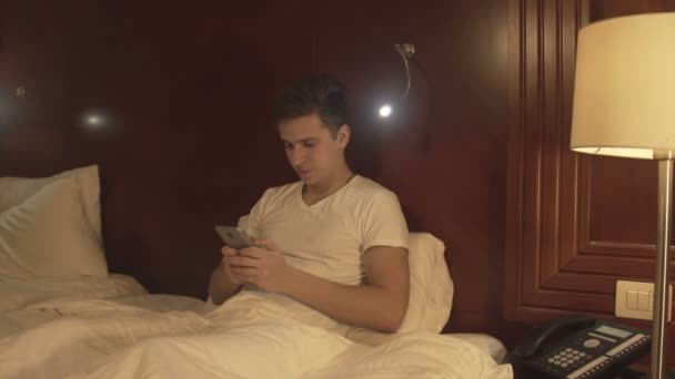 Relaxed young man holding the phone typing message - Imágenes, Vídeo