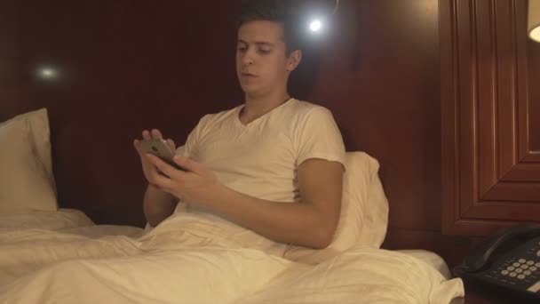 Relaxed young man holding the phone typing message - Filmmaterial, Video