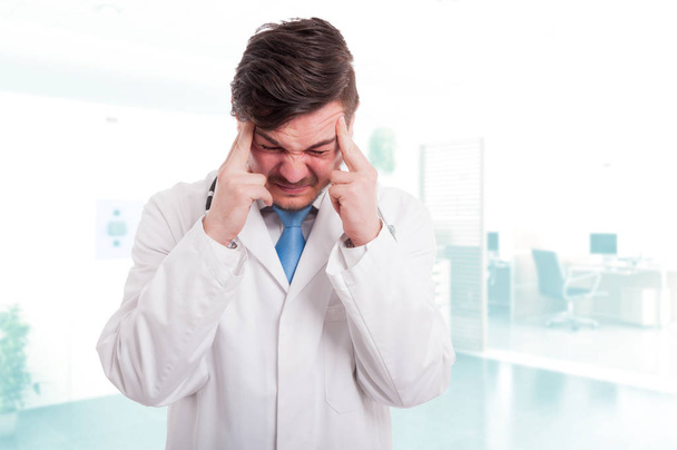 Valkoihoinen mies lääkäri päänsärky näyttää uupuneelta
 - Valokuva, kuva