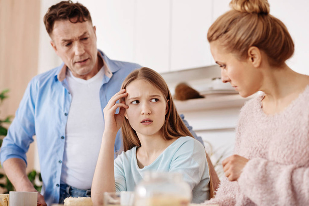 Cheerless moody girl discussing problems with her parents - Photo, Image