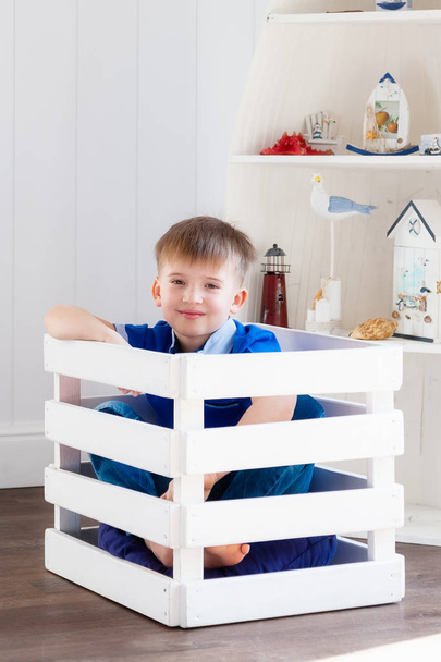 Portrait of a boy sitting in a box in the nursery - Foto, afbeelding