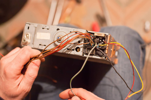Specialist repair the old car radio cassetter recorder on knee - 写真・画像