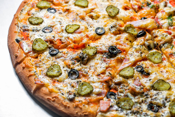 pizza with sausage and pickles, by cut to pieces on a metal table. selective focus on the filling close-up. - Photo, Image