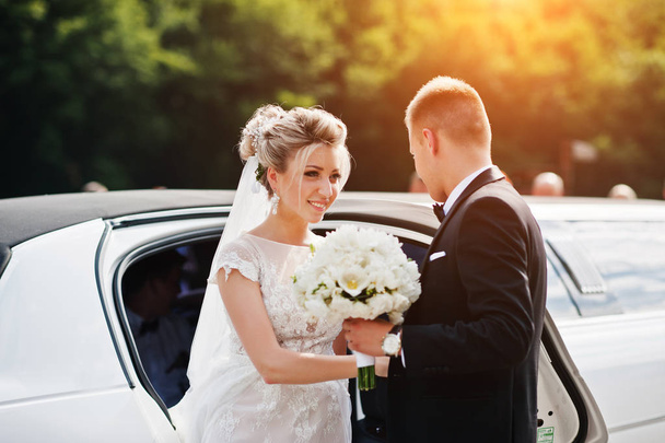 Groom give his hand for bride to take from limousine at wedding  - Фото, зображення