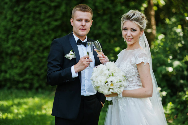 Stylish and gorgeous wedding couple with glasses of champagne. - Foto, afbeelding