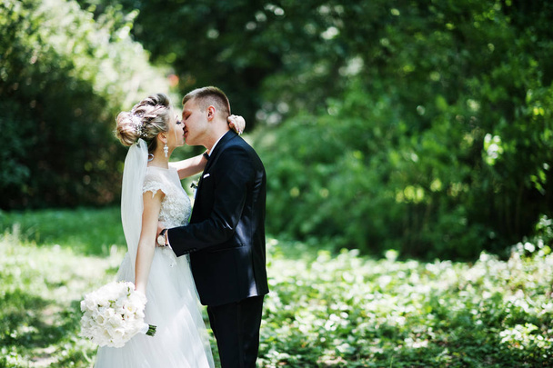 Stylish and gorgeous kissing wedding couple walking outdoor at p - Фото, изображение
