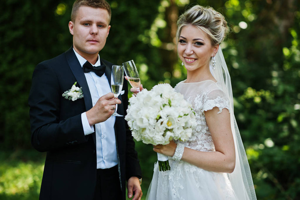 Stylish and gorgeous wedding couple with glasses of champagne. - Фото, зображення