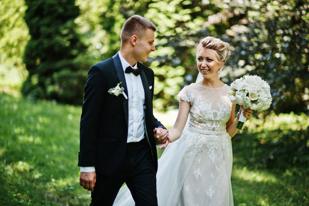 Stylish and gorgeous wedding couple walking outdoor at park on s - Foto, Imagen