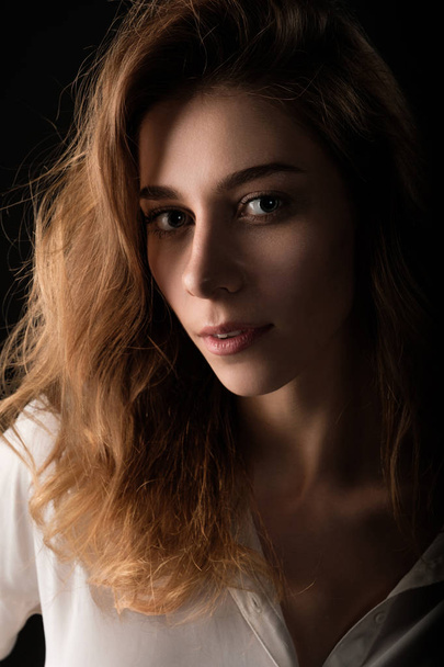 close up studio portrait of young woman in white blouse on black background - Foto, Imagem