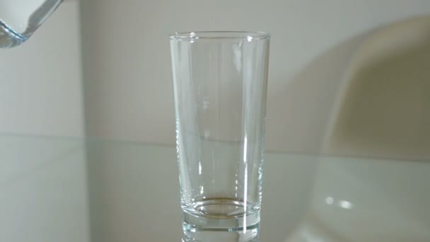 El agua de una jarra se vierte en un vaso alto
 - Metraje, vídeo