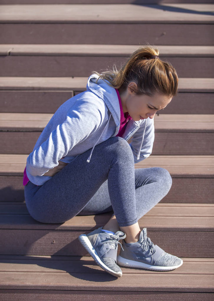 woman with abdominal pain sitting on the steps - Photo, Image