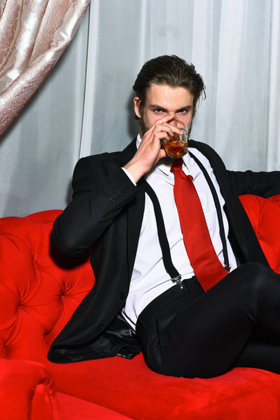 bearded man, businessman holding glass of whiskey in red tie - Фото, зображення