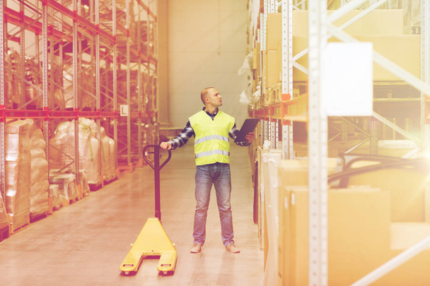 man with loader and clipboard at warehouse - Foto, Imagen